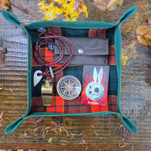 Multicolored pouch with nature-themed items on a wooden surface surrounded by autumn leaves.