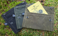 Three green fabric pouches on a grassy background