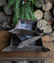 Fabric pouches on a wooden surface with greenery and logs in the background