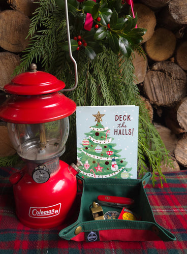Red lantern with Christmas card and wreath on wooden logs and plaid fabric