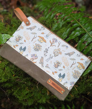 zipper pouch with mushroom pattern on a green leaf background
