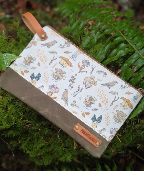 zipper pouch with mushroom pattern on a green leaf background