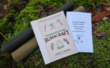 Two books on a mossy surface, one titled 'Traditional Bushcraft' by Craig Caudill.