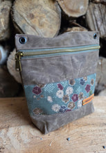 Gray pouch with floral patterned flap on a wooden background