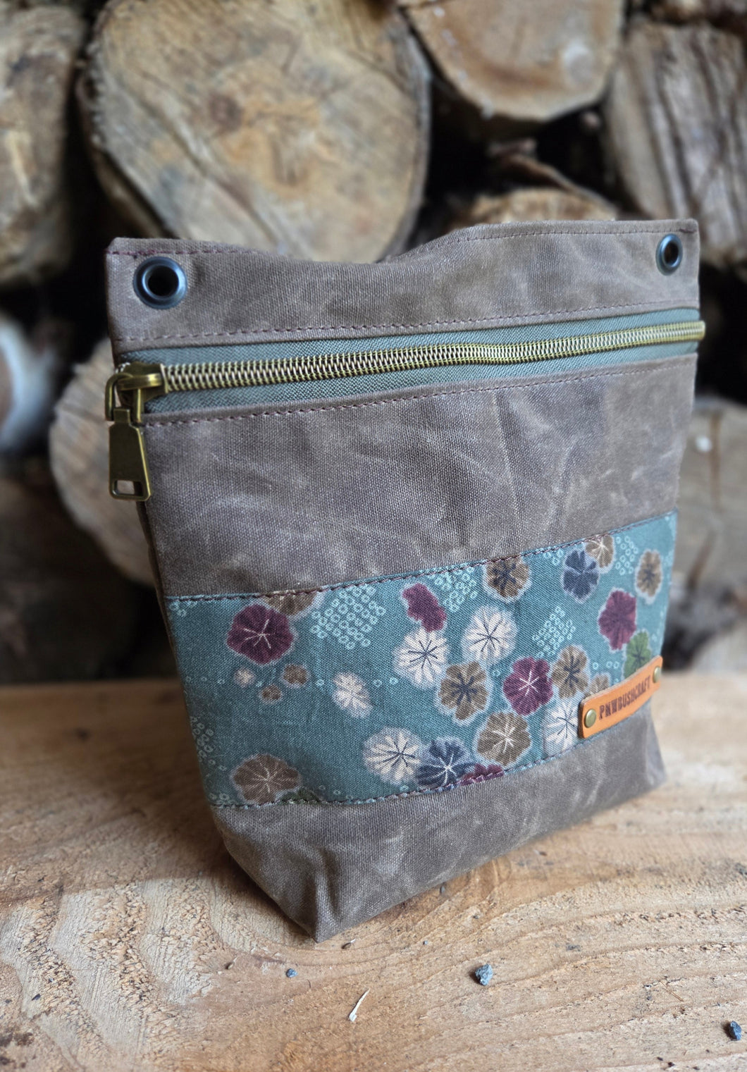 Gray pouch with floral patterned flap on a wooden background