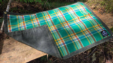 Plaid fabric with green, orange, and blue pattern on a wooden surface