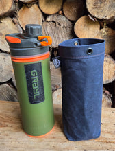 Green GRAYL water filter bottle with blue carrying case on wooden logs